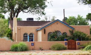 A mixed style, part territorial part phuble style home with tan stucco and blie trim on Monte Vista Blved in Albuquerque's University District
